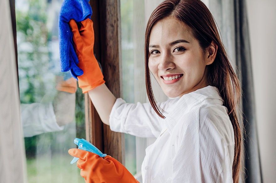 Smiling SpaHa cleaner in gloves wiping down a window